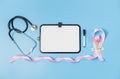 One pink ribbon, tulip, stethoscope and blank whiteboard on blue. Royalty Free Stock Photo