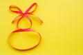 Pink ribbon in the form of number eight on a yellow background. Congratulations on the International Women`s Day, March 8th