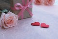 Pink ribbon gift box, orange-pink roses and red satin hearts on vintage wooden table for Valentine& x27;s concept Royalty Free Stock Photo