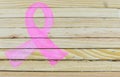 A pink ribbon shape is hand-painted on natural, raw wood planking with copy space on the right side.