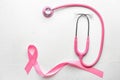 Pink ribbon and stethoscope on light background. Breast cancer awareness concept Royalty Free Stock Photo