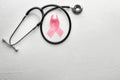 Pink ribbon and stethoscope on light background. Breast cancer awareness concept Royalty Free Stock Photo