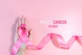 Pink ribbon symbol. Breast Cancer Awareness Month Campaign. Woman hand hold the pink ribbon on pink background