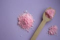 Pink rose bath salt with wooden spoon on lilac background. Aroma spa concept. Aromatherapy. Royalty Free Stock Photo