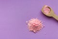 Pink rose bath salt with wooden spoon on lilac background with copy space. Aroma spa concept. Aromatherapy . Royalty Free Stock Photo