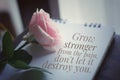 Pink rose on a book with inspirational motivational message - Grow stronger from the pain, do not let it destroy you.
