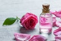 Pink rose flower and glass of bottle essential oil or rose water with rose petals
