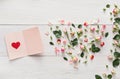 Valentine background with pink rose flowers heart, handmade paper card on white rustic wood. Royalty Free Stock Photo