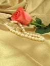 Pink rose and pearls on gold satin Royalty Free Stock Photo