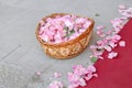 Pink rose petals in a basket and scattered on the floor next to a red carpet Royalty Free Stock Photo