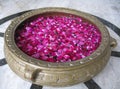 Rose petals in a large vase of water on a marble floor