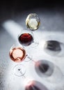 Pink rose,red and white wine glasses on light background with shadows Royalty Free Stock Photo