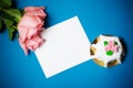 Pink roses, card and cake with pink marzipan roses on blue background Royalty Free Stock Photo