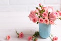 Pink roses flowers in blue cup against white brick wall. Royalty Free Stock Photo