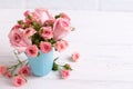 Pink roses flowers in blue cup against white brick wall. Royalty Free Stock Photo