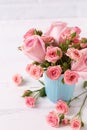 Pink roses flowers in blue cup against white brick wall. Royalty Free Stock Photo