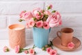 Pink roses flowers in blue cup, burning candle and little cup for coffee against white brick wall. Royalty Free Stock Photo