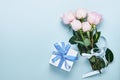 Pink roses flowers bouquet with ribbon and gift box over beautiful blue background. Greeting card template with copy space Royalty Free Stock Photo