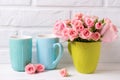 Pink roses flowers and colorful blue cups against white brick w Royalty Free Stock Photo