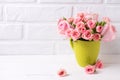 Pink roses flowers in green cup against white brick wall. Royalty Free Stock Photo