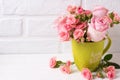 Pink roses flowers in green cup against white brick wall. Royalty Free Stock Photo