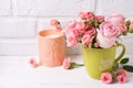 Pink roses flowers in green cup and candle against white brick Royalty Free Stock Photo