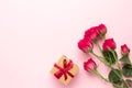 Pink roses flowers and present gift on pink background with copyspace. Minimalistic composition for Valentine`s day day and Royalty Free Stock Photo