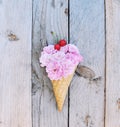 Pink roses flowers topped with a red cherries in ice cream cone on rustic wooden background Royalty Free Stock Photo