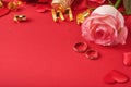 Pink roses flowers, wedding rings, champagne, gift, golden ribbons and confetti hearts on red background. Top view with space for Royalty Free Stock Photo