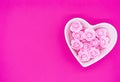 Roses laid out in the shape of a heart on a bright pink backdrop. Valentine`s day background. Empty copy space for your text.