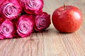 5 pink roses on a wooden background with an Apple