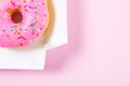 Pink round donut in the box on pastele background. Flat lay, top view.