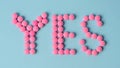 Pink round pills forming the word YES in english text as positive message towards health protection