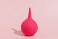 Pink rubber enema on pink isolated background. The concept of cleaning and detoxing the body, medical and pharmaceutical products