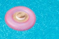 A pink rubber ring on which lies a straw hat floats on the surface of the water with highlights in the pool. Vacation concept, bac