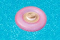 A pink rubber ring on which lies a straw hat floats on the surface of the water with highlights in the pool. Vacation concept, bac