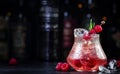 Pink rum alcoholic cocktail drink with white rum, pineapple juice, cranberries, raspberries and ice. Black bar counter background Royalty Free Stock Photo