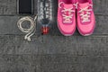 Beautiful pink sneakers, headphones, water and apples on a wooden dark floor. View from above. Royalty Free Stock Photo