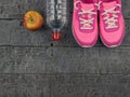 Pink running shoes for fitness classes at the gym and a ripe Apple on a wooden floor. View from above. Royalty Free Stock Photo