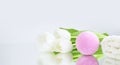 A pink salt bomb on a white gray background is reflected, next to white tulips and a towel. Mineral makeup. Banner. Spa care. Copy Royalty Free Stock Photo