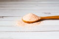 Fine pink Himalayan salt in wooden spoon on a white wooden background