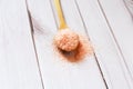 Fine pink Himalayan salt in wooden spoon on a white wooden background