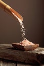 Pink salt is poured with a wooden spoon in the wooden dish Royalty Free Stock Photo