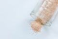 pink salt spill from small glass container on white background