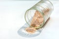 pink salt spill from small glass container on white background