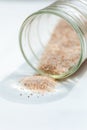 pink salt spill from small glass container on white background