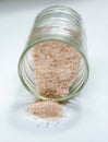 pink salt spill from small glass container on white background