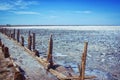 Pink salty lake with path, hedged by weathered old wooden sticks