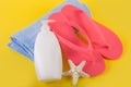 Pink sandal flip flop on blue towel and suntan cream lotion and starfish on yellow background