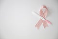 Pink satin breast cancer awareness ribbon with blank pregnancy test isolated on white background top view
